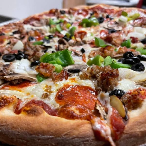 Close-up of a Mercato's Italian Grill pizza with pepperoni, sausage, green peppers, olives, and mushrooms.