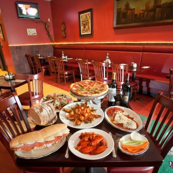 A table laden with Mercato's Italian dishes, including pizza, pasta, seafood, and a large sub sandwich.